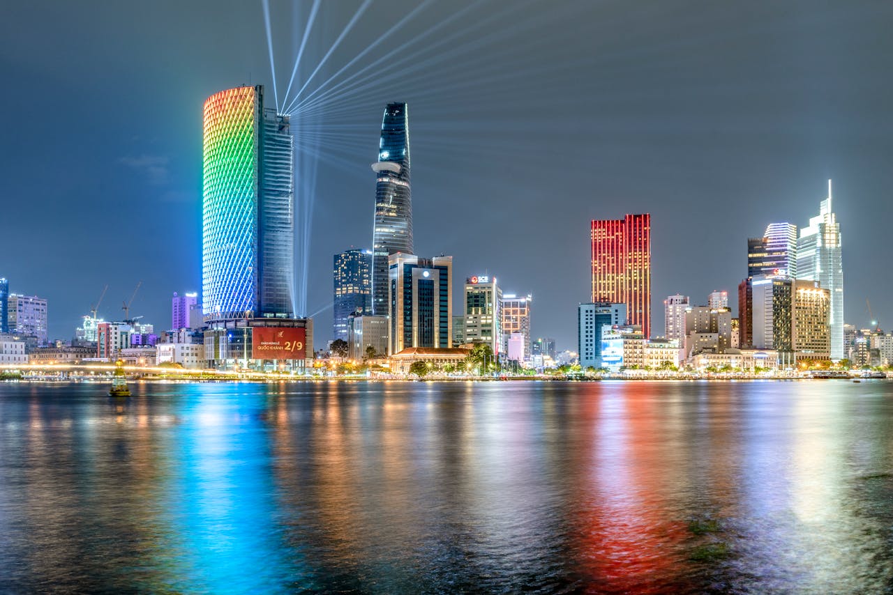 pexels-photo-17327394 Colorful night view of Ho Chi Minh City skyline with illuminated skyscrapers reflecting on the Saigon River.